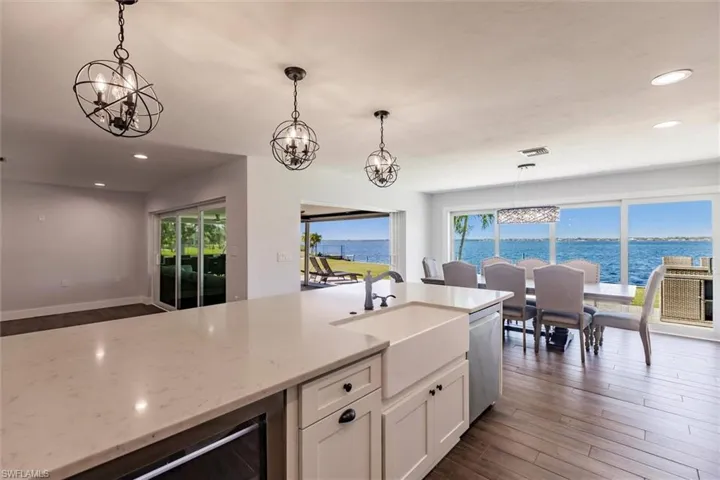 Kitchen featuring decorative light fixtures, a water view, light stone countertops, stainless steel dishwasher, and a sink