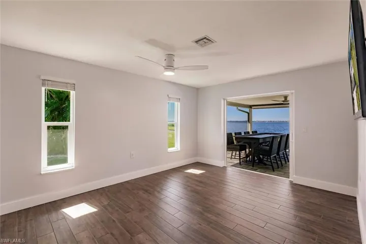 Spare room with ceiling fan, dark wood-style flooring, plenty of natural light, and visible vents