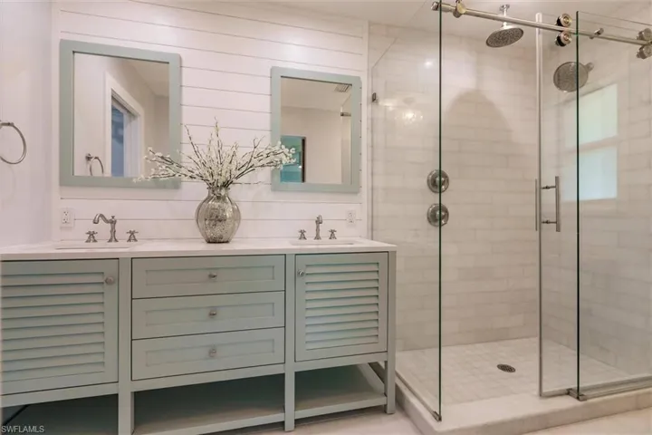 Bathroom featuring a stall shower, a sink, and double vanity