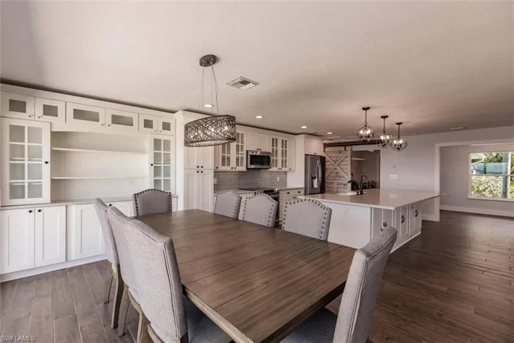 Dining area featuring dark wood-style flooring, recessed lighting, visible vents, and baseboards