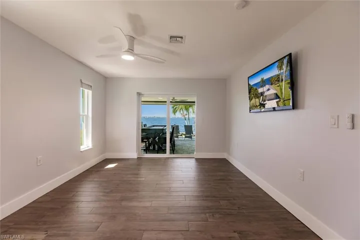 Empty room featuring dark wood-style floors, visible vents, ceiling fan, and baseboards