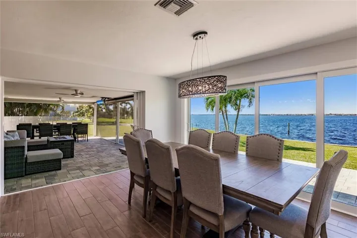 Dining area with dark wood-type flooring, a water view, visible vents, and a ceiling fan