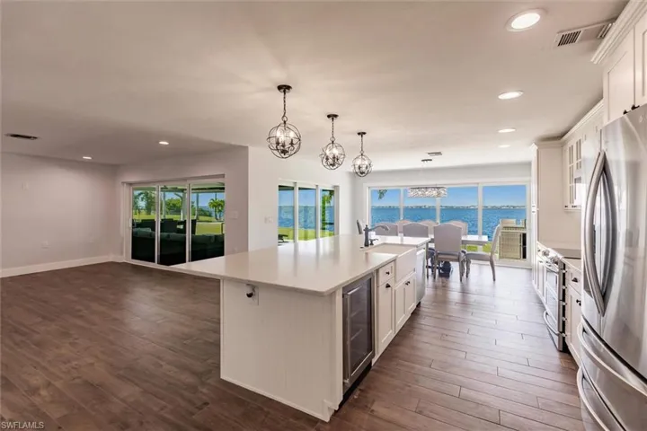 Kitchen featuring a water view, a center island with sink, appliances with stainless steel finishes, and white cabinets