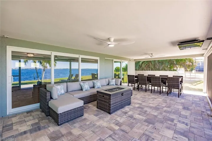 View of patio with a ceiling fan, outdoor dining space, an outdoor living space with a fire pit, and a water view