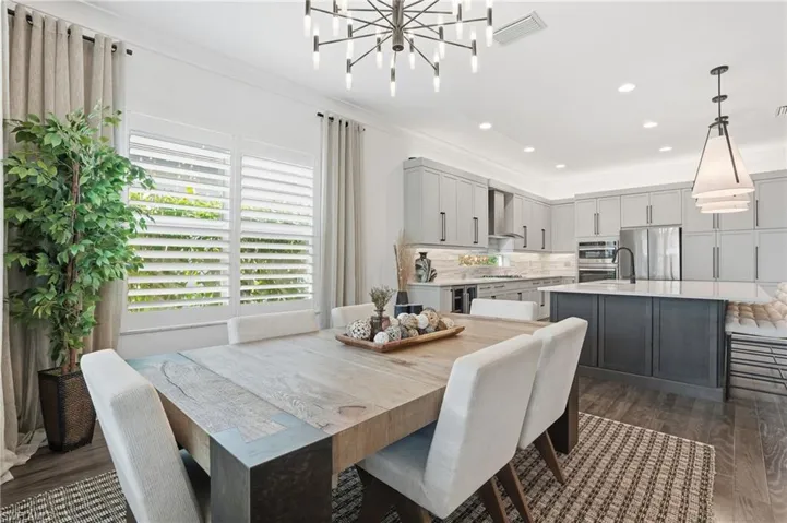 Dining space with dark wood-style floors, ornamental molding, recessed lighting, and a chandelier