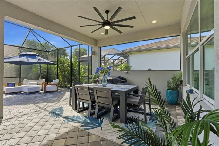 View of patio featuring outdoor dining area, glass enclosure, a ceiling fan, a sunroom, and an outdoor hangout area