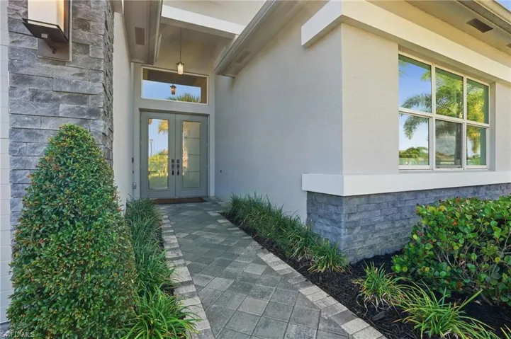 Doorway to property with stucco siding, stone siding, and french doors