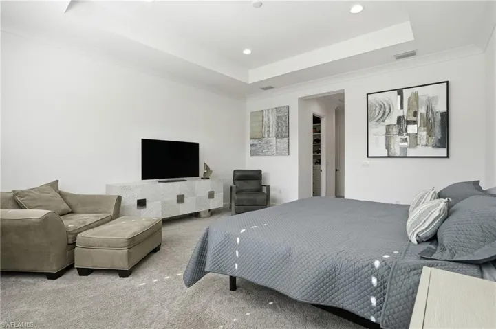 Carpeted bedroom featuring a raised ceiling and recessed lighting