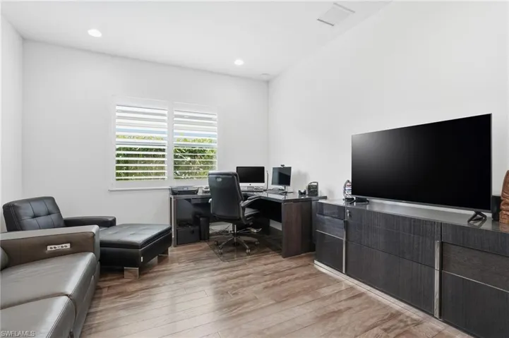 Office with light wood-type flooring and recessed lighting