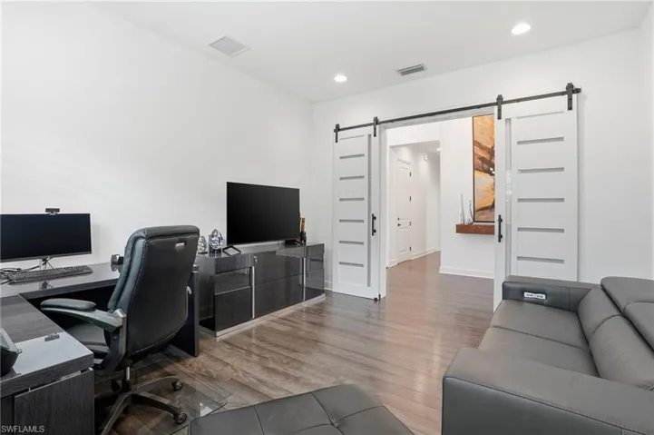Office space with wood finished floors, a barn door, and recessed lighting