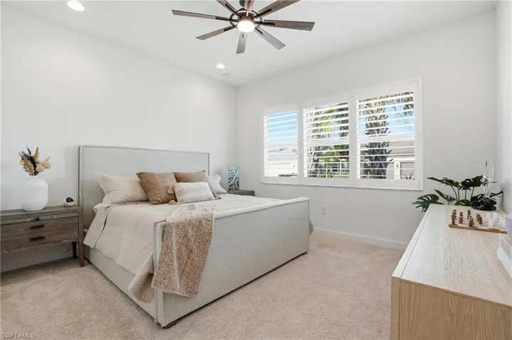 Bedroom featuring light colored carpet, a ceiling fan, and recessed lighting