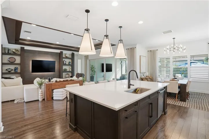 Kitchen with open floor plan, decorative light fixtures, dark wood-style floors, crown molding, and a chandelier