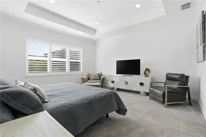 Carpeted bedroom with a tray ceiling and recessed lighting