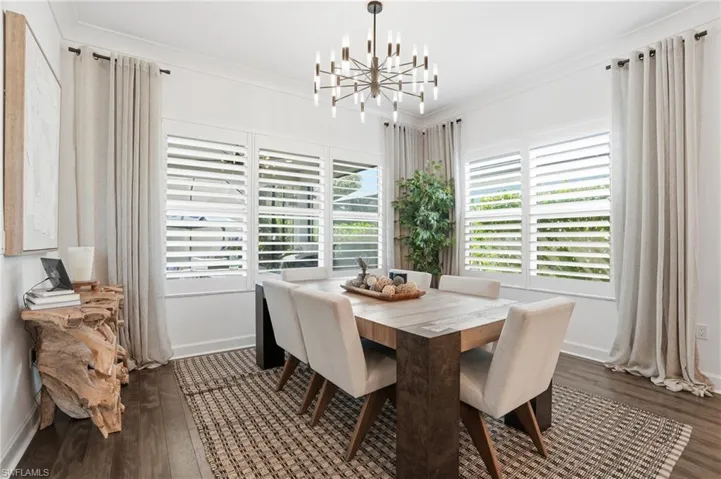 Dining room with a chandelier, dark wood finished floors, and ornamental molding