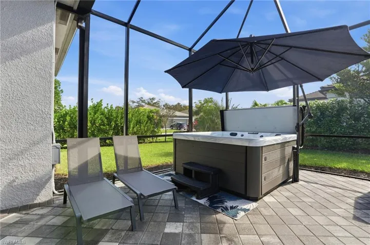 View of patio featuring a hot tub, glass enclosure, and a sunroom