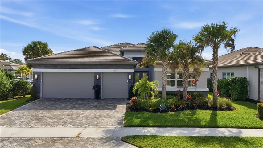 View of front of property featuring an attached garage, decorative driveway, a front yard, stucco siding, and a tile roof