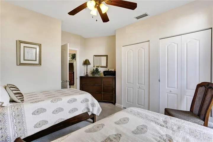 Tiled bedroom with ceiling fan and two closets
