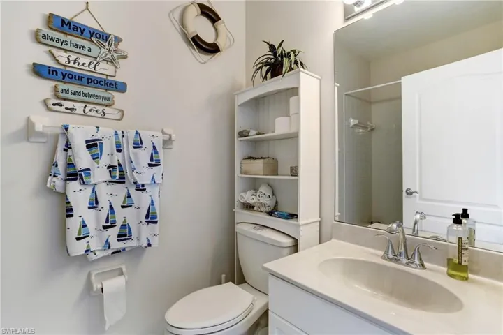 Bathroom featuring a tile shower, vanity, and toilet