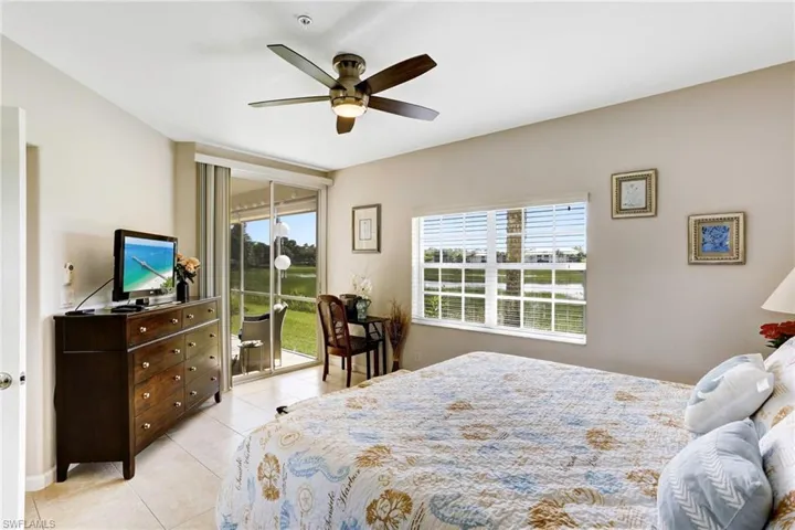 Tiled masterbedroom featuring ceiling fan and access to outside