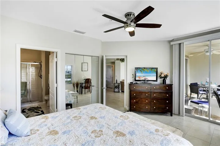 Tiled masterbedroom featuring ceiling fan, ensuite bath, and access to outside