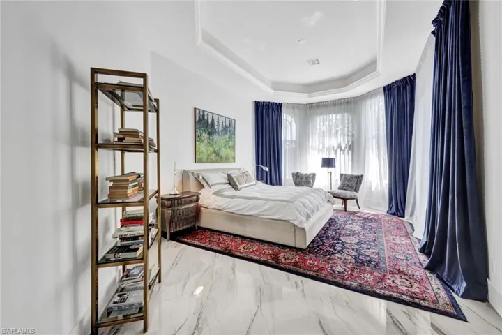Primary bedroom with tray ceiling and crown molding detail! Privacy curtains that still allow the natural light to flow. Wonderful neutral tile carried throughout home!