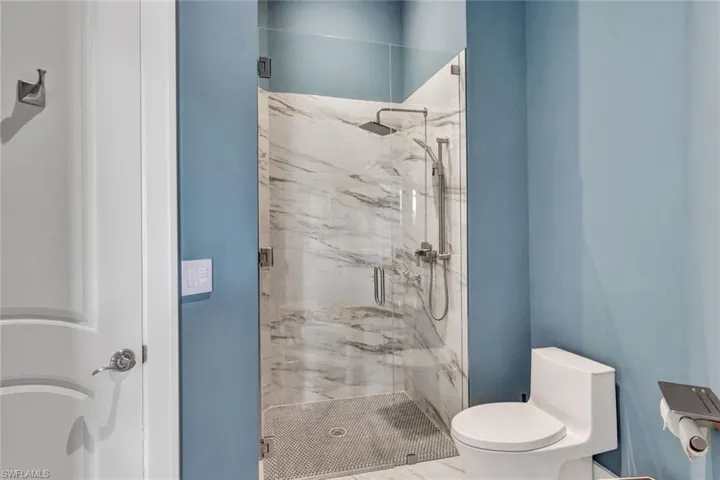 Guest bathroom with frameless glass shower door, spray bar, rainfall shower head, and lovely penny round porcelain shower floor tile!