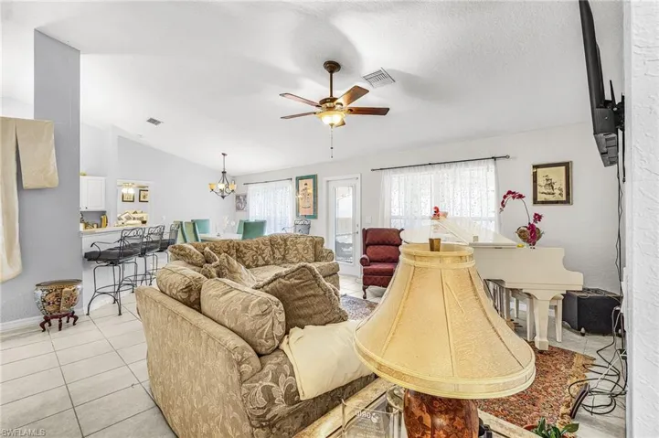 Living room featuring light tile patterned floors, a chandelier, and ceiling fan
