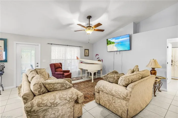 Living room featuring ceiling fan, lofted ceiling, and light tile patterned floors