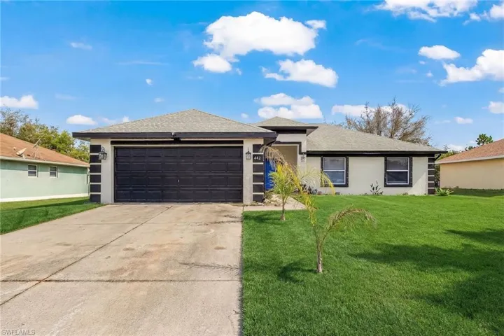 View of front of house featuring a front lawn, concrete driveway, a garage, stucco siding, and a shingled roof