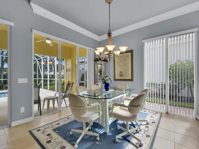 Dining space featuring crown molding, light tile patterned floors, and ceiling fan with notable chandelier