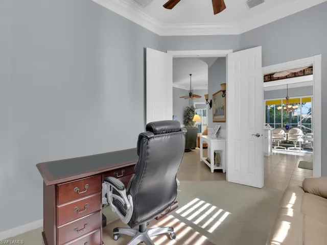 Tiled office space featuring ceiling fan with notable chandelier and ornamental molding