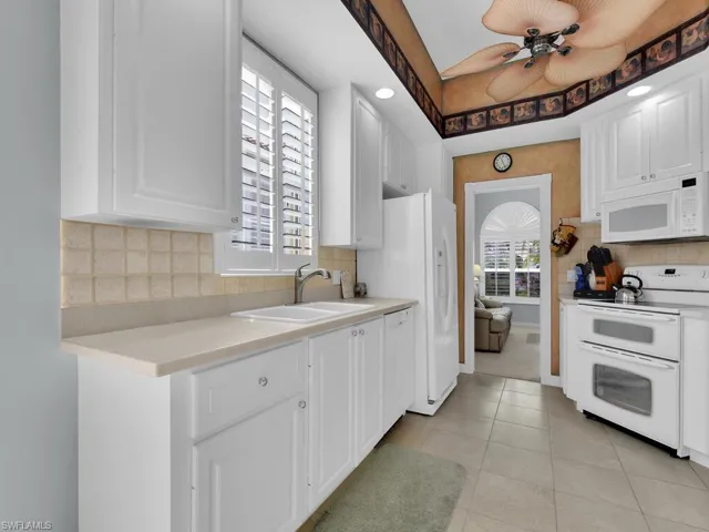 Kitchen with white cabinets, white appliances, plenty of natural light, and sink