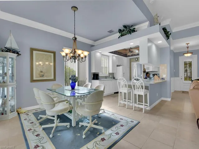Dining area with ornamental molding, sink, light tile patterned floors, and a chandelier