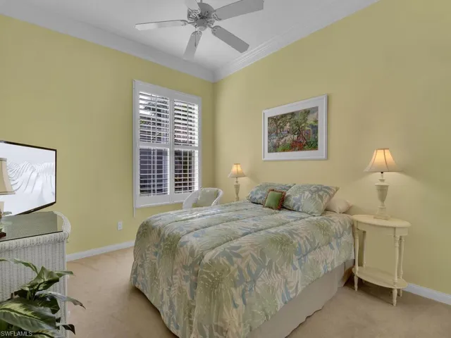 Carpeted bedroom with ceiling fan and ornamental molding
