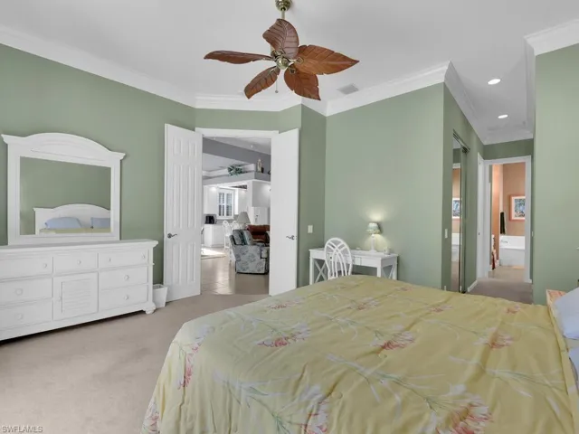Carpeted bedroom with ceiling fan, crown molding, and multiple windows