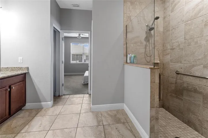 Bathroom with a tile shower, tile flooring, and vanity