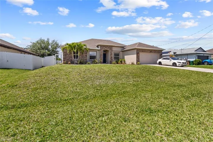 View of front facade featuring a garage and a front lawn