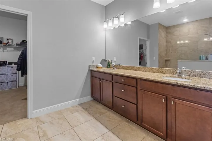Bathroom with tile flooring, double sink, and vanity with extensive cabinet space
