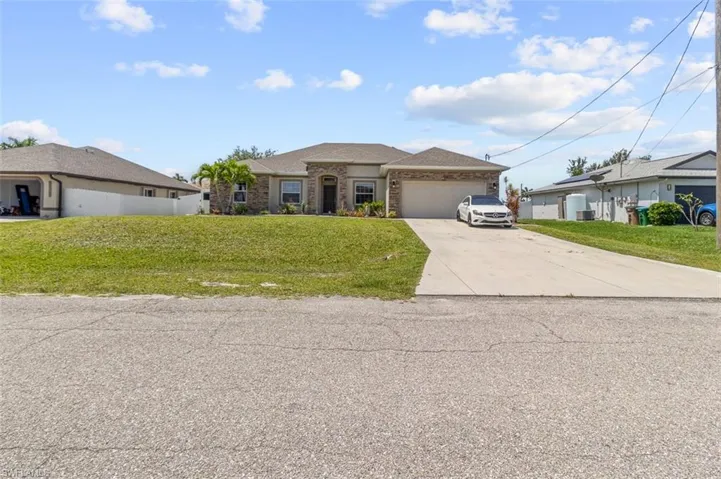 Ranch-style home featuring a garage and a front lawn