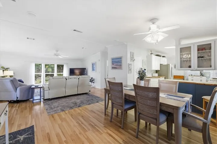 Dining room featuring a ceiling fan, crown molding, light wood-style floors, and vaulted ceiling