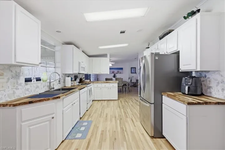 Kitchen featuring butcher block counters, decorative backsplash, and white cabinets