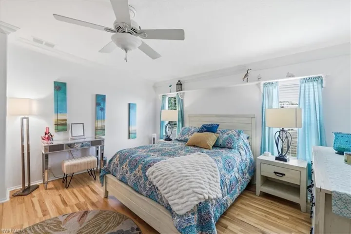 Bedroom with light wood finished floors, ceiling fan, and ornamental molding