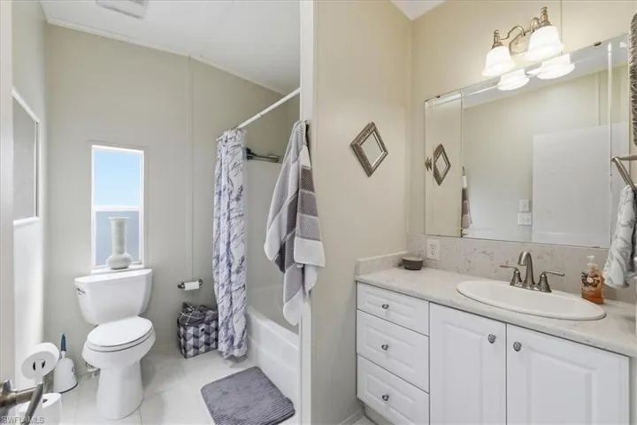 Full bath featuring vanity, shower / tub combo with curtain, and light tile patterned floors