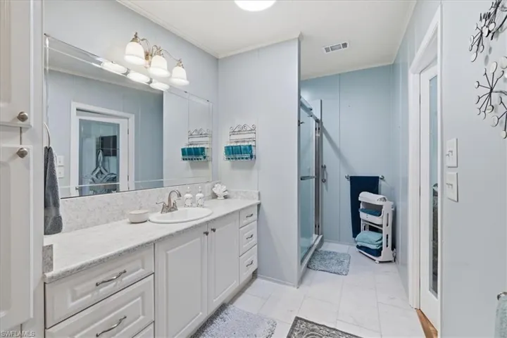 Full bathroom with vanity, a shower stall, and crown molding