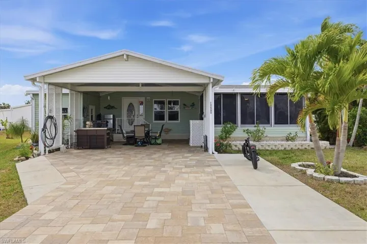Rear view of house featuring a sunroom, a patio, and a lawn