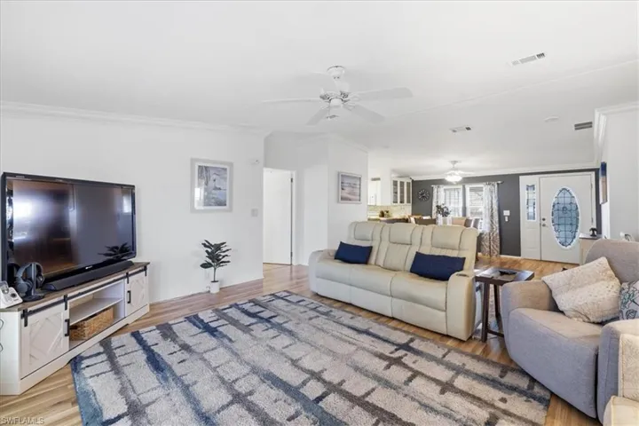 Living room featuring crown molding, light wood finished floors, and a ceiling fan