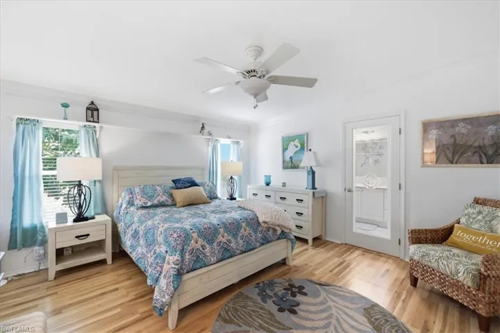 Bedroom with ornamental molding, light wood-style floors, and a ceiling fan