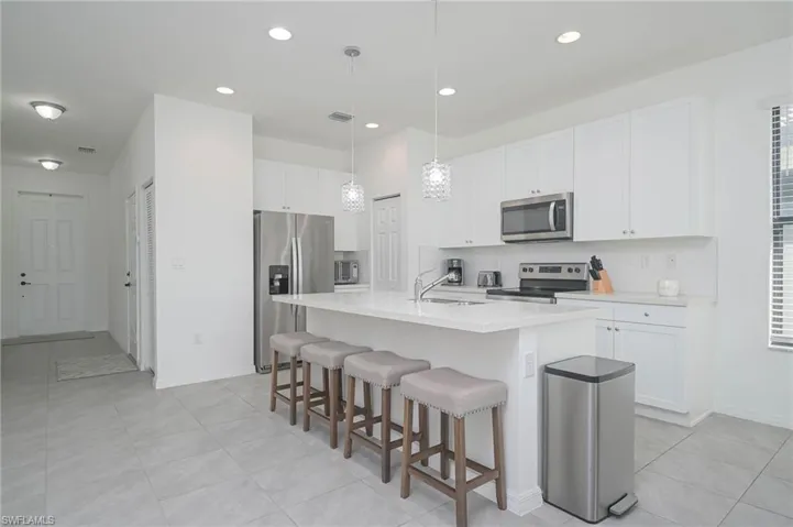 Kitchen with appliances with stainless steel finishes, a sink, tasteful backsplash, a kitchen bar, and recessed lighting