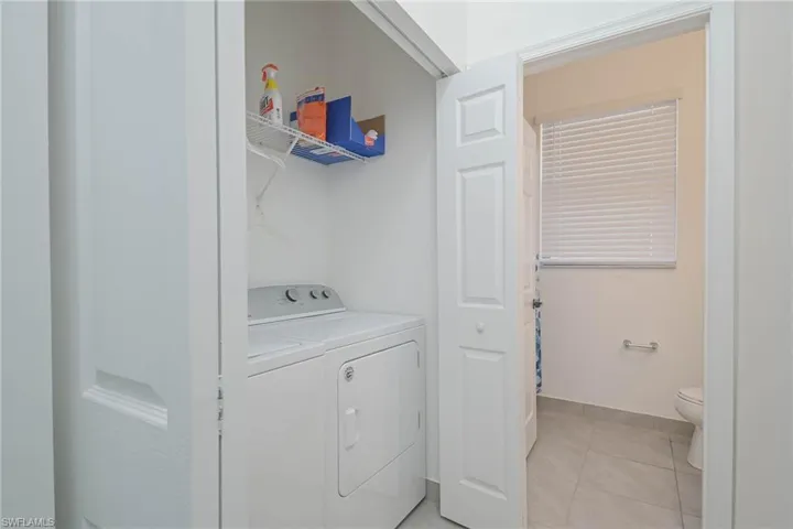 Laundry room featuring separate washer and dryer, light tile patterned floors, and baseboards