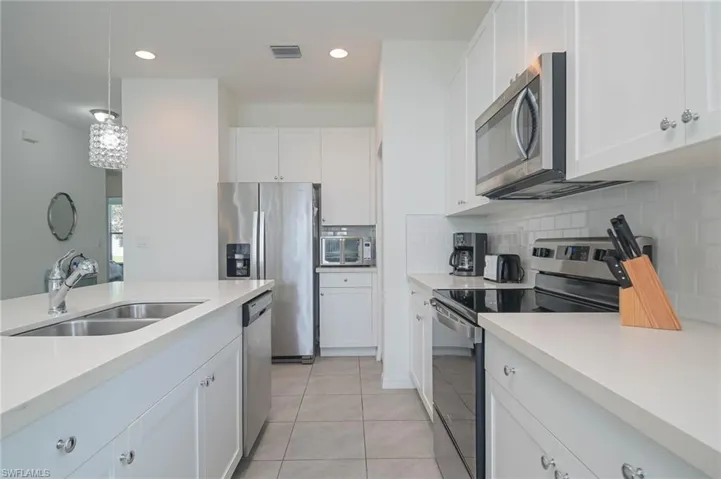 Kitchen featuring appliances with stainless steel finishes, a sink, light countertops, light tile patterned flooring, and recessed lighting